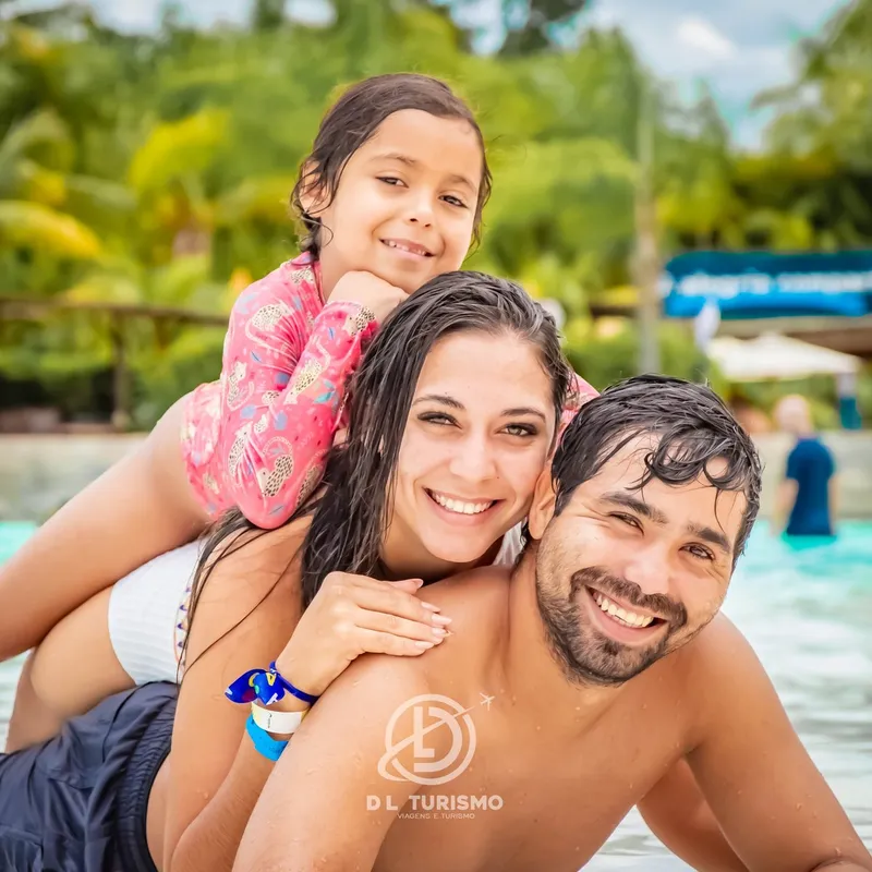 Família sorrindo na piscina de um parque aquático.